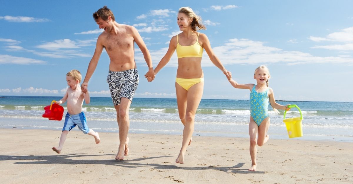 family on the beach smiling 2 adults 2 children